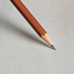 Detailed close-up of a wooden pencil resting on white paper, perfect for educational themes.